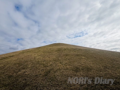 空に向かってそびえる急斜面の山（芝山）