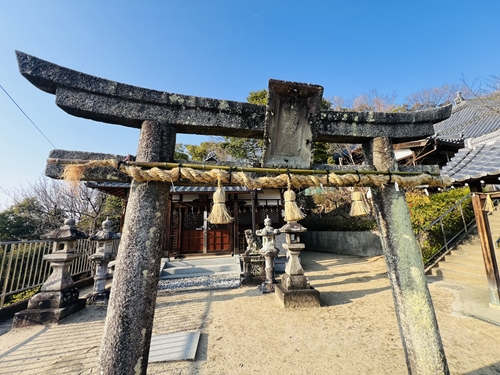 野崎観音の隣に位置する南條神社の、風格ある石造りの鳥居と境内。鳥居には立派な注連縄（しめなわ）が張られ、石灯籠が並ぶ。奥に見える社殿には、御祭神であるスサノオノミコト（牛頭天王）が祀られている。