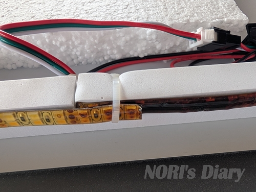 衝撃的な放熱不良箇所。発泡スチロールと硬質スポンジの間にLEDテープが挟まれ、あろうことかタイラップで締め付けられている。LEDテープは熱で茶色く焼損している。